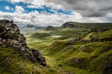 green grass on mountain under white cloudy sky