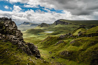 green grass on mountain under white cloudy sky