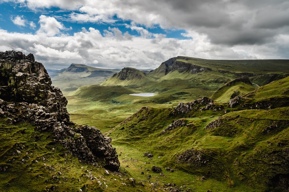 green grass on mountain under white cloudy sky