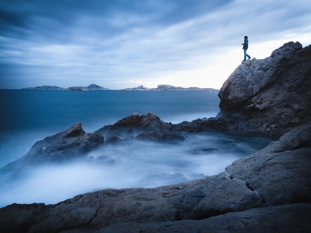 man standing on mountain cliff by the sea