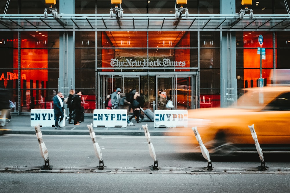 Zeitrafferfoto eines gelben Taxis, das an der NYT vorbeifährt