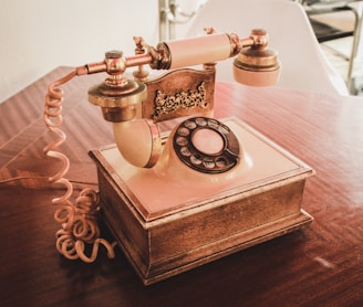 white and brown rotary telephone on brown wooden table