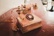 white and brown rotary telephone on brown wooden table