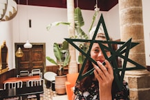 woman holding two star decors in front of her face