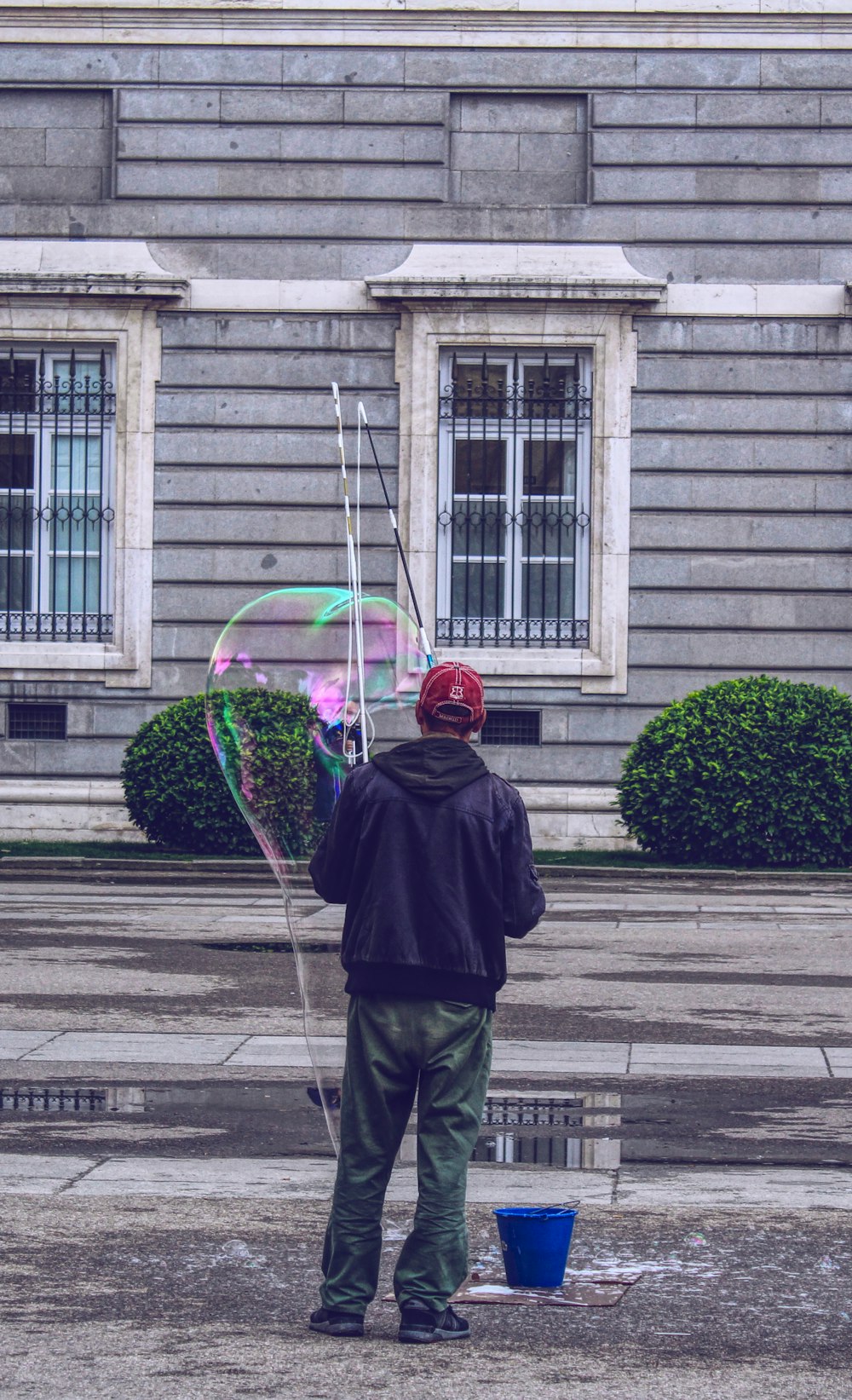 man forming giant bubble outside house