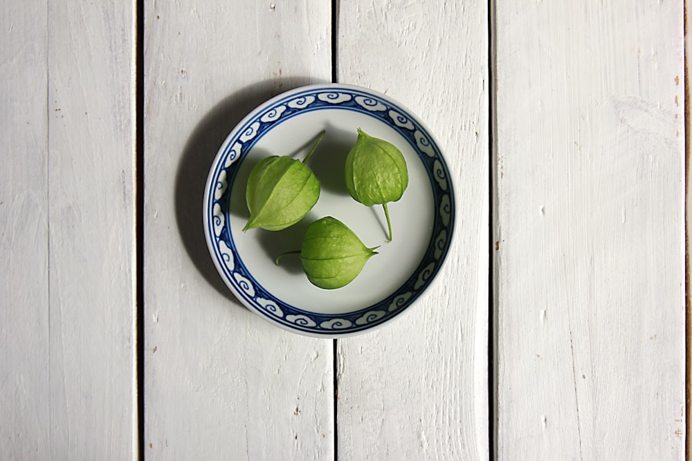 three green leaves in a blue and white bowl