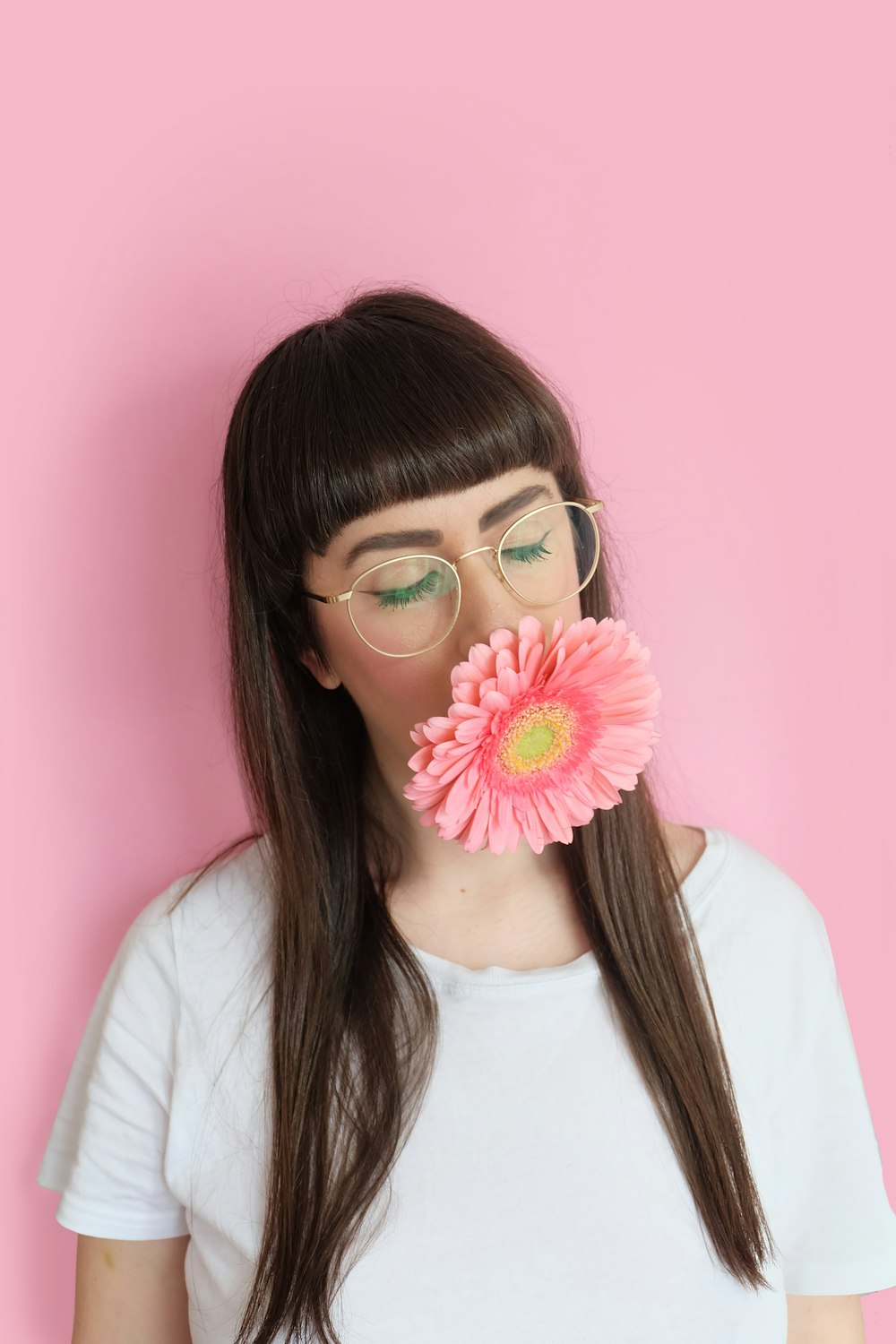 woman wearing eyeglasses with flower in mouth