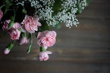 Soft pink and white carnations bundled together with rustic twine on a wooden table.