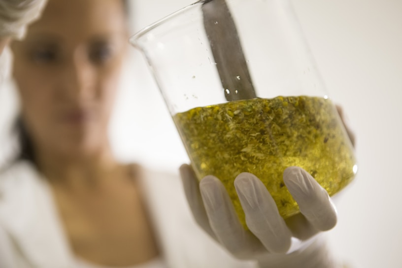 Close-up of a technician carefully blending colorful cleaning compounds in a lab beaker.