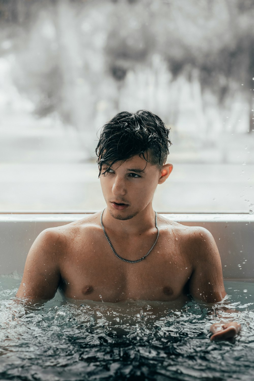 man wearing black necklace in pool