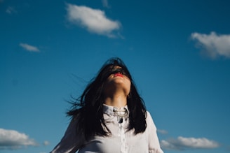 woman wearing white button-up top under blue sky