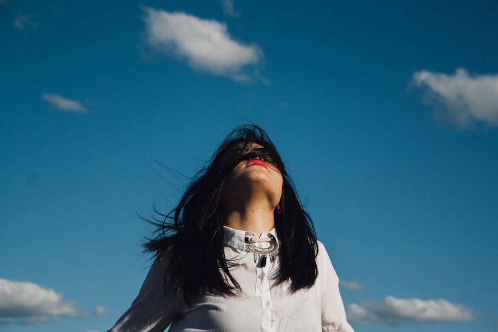 woman wearing white button-up top under blue sky