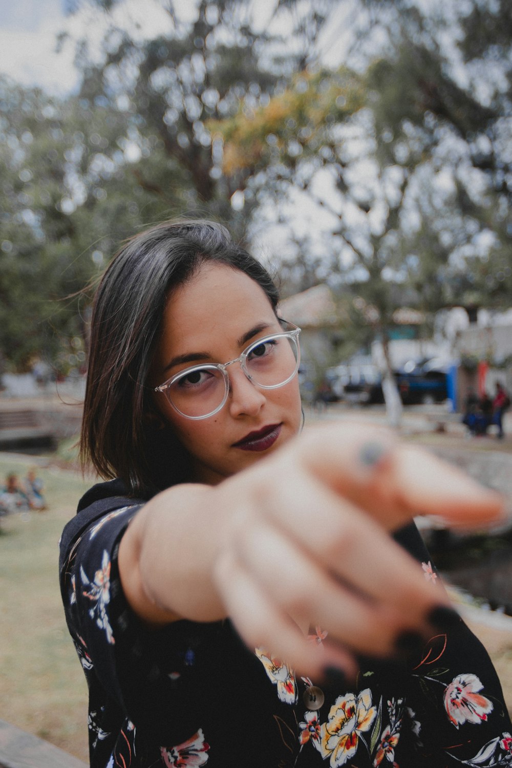 woman wearing eyeglasses pointing her hand during daytime