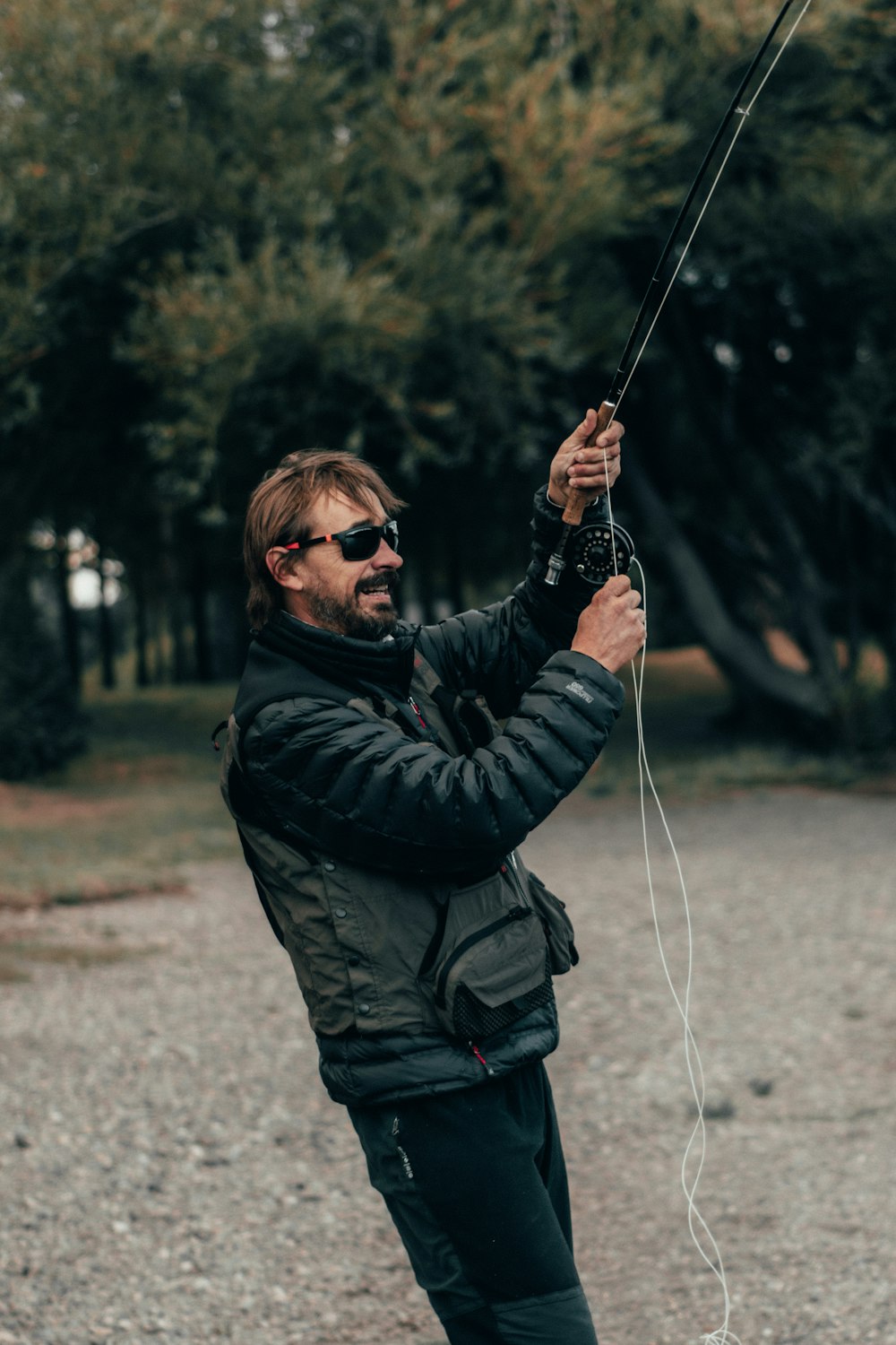 man wearing black jacket and pants with sunglasses holding white rope