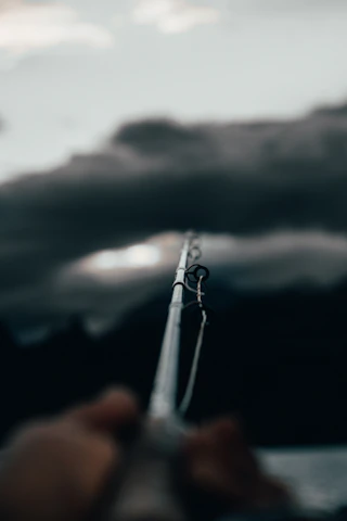 Close-up of a fishing influencer holding a high-end rod, smiling against a serene Florida shoreline at dawn.