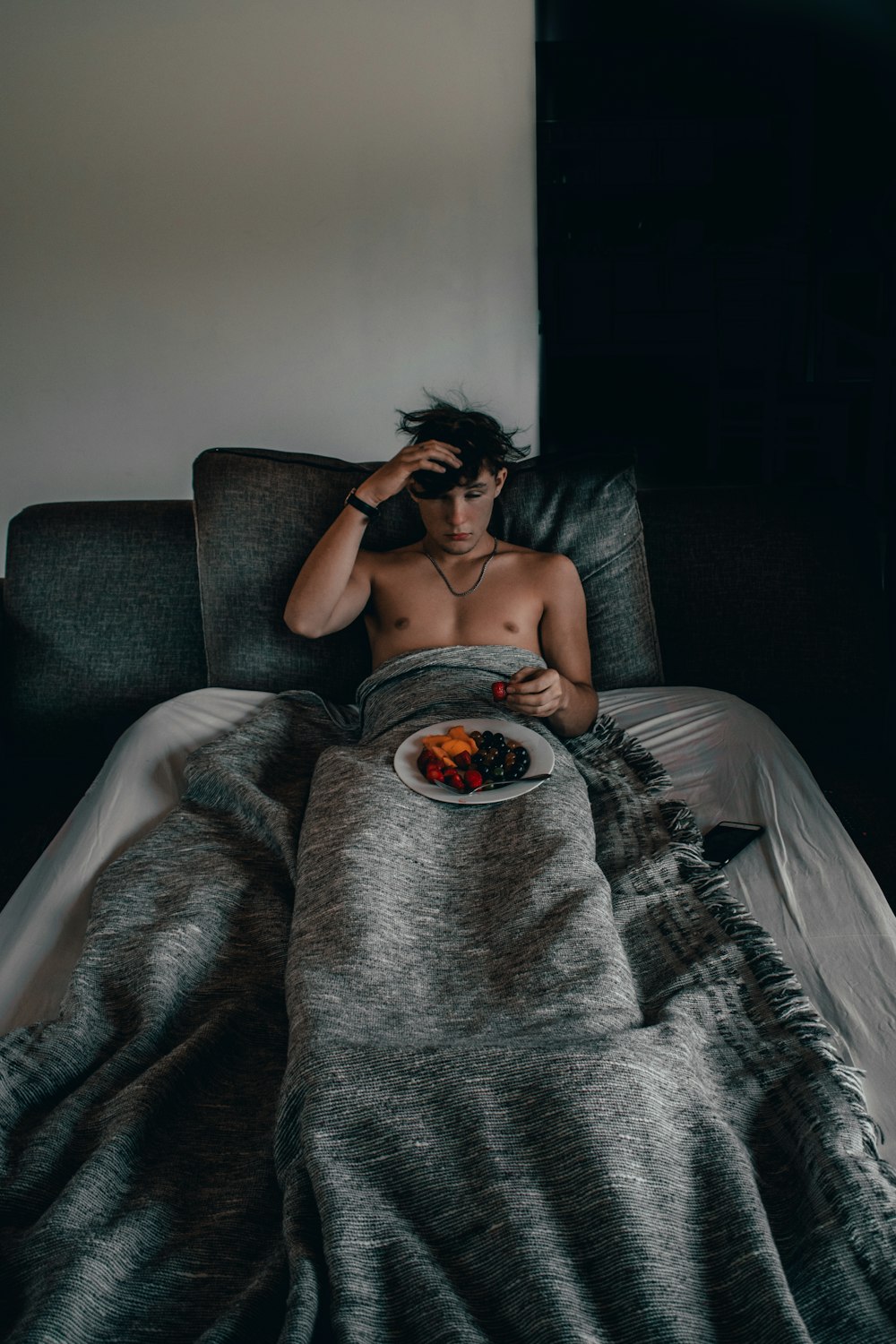 man lying on bed with foods on lap