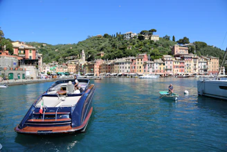 A sunlit harbor view of colorful houses and boats docked on Symi Island.