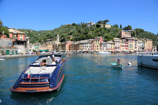 A sunlit harbor view of colorful houses and boats docked on Symi Island.