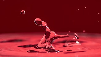 a drop of water that is falling into a red bowl