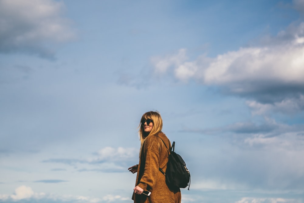 woman wearing brown coat with black backpack