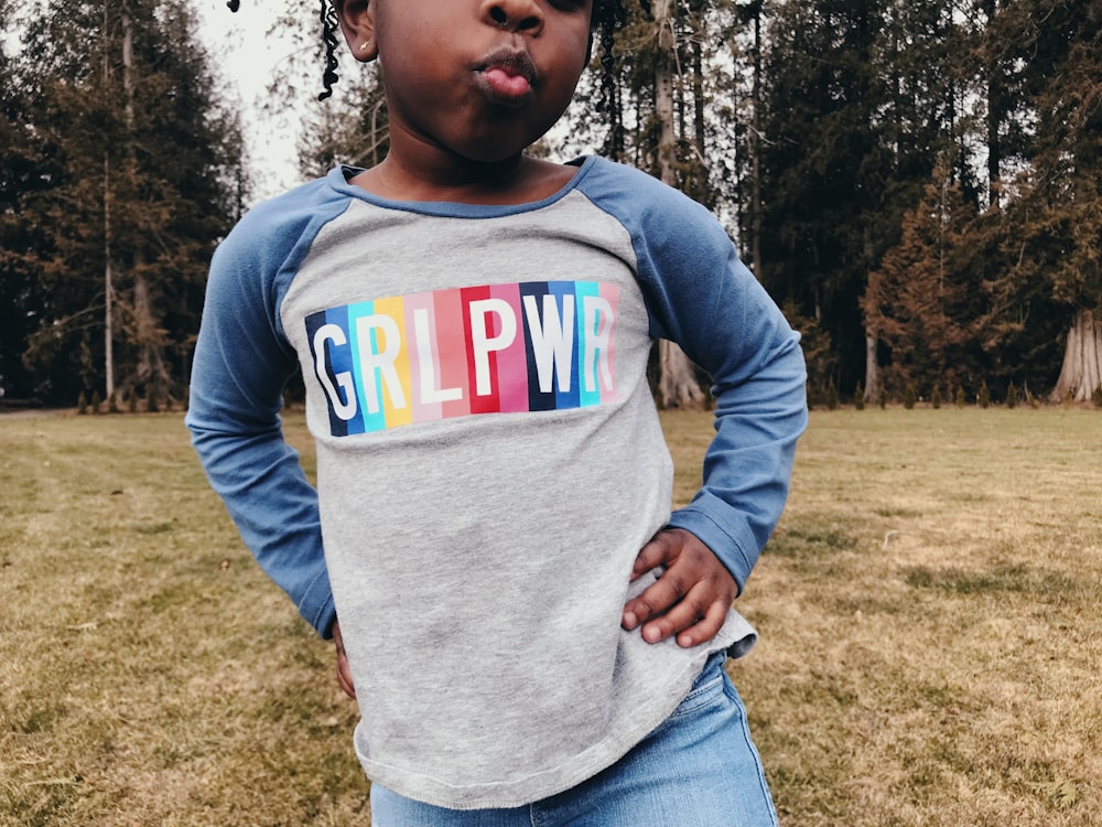 enfant debout au milieu d’un champ d’herbe