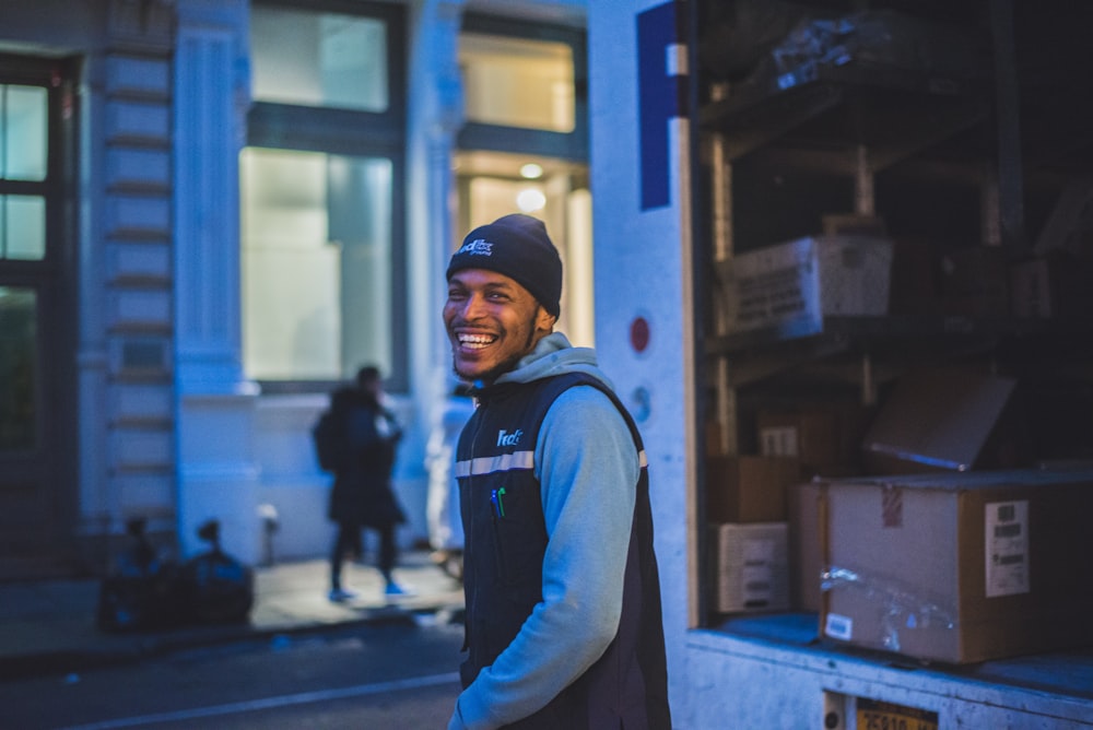 Homem sorridente fica atrás de caminhão de entrega