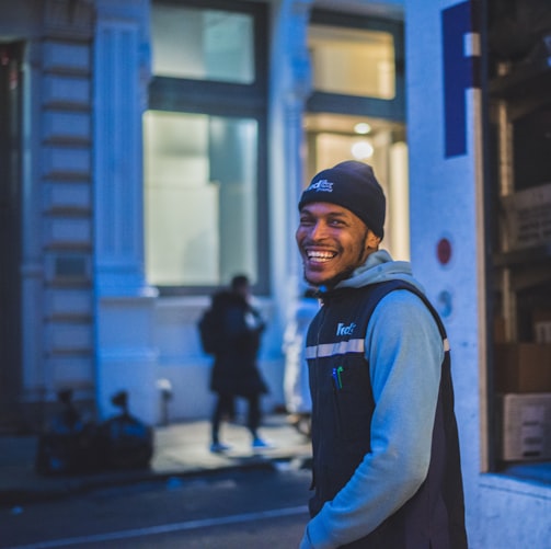 smiling man stands behind delivery truck