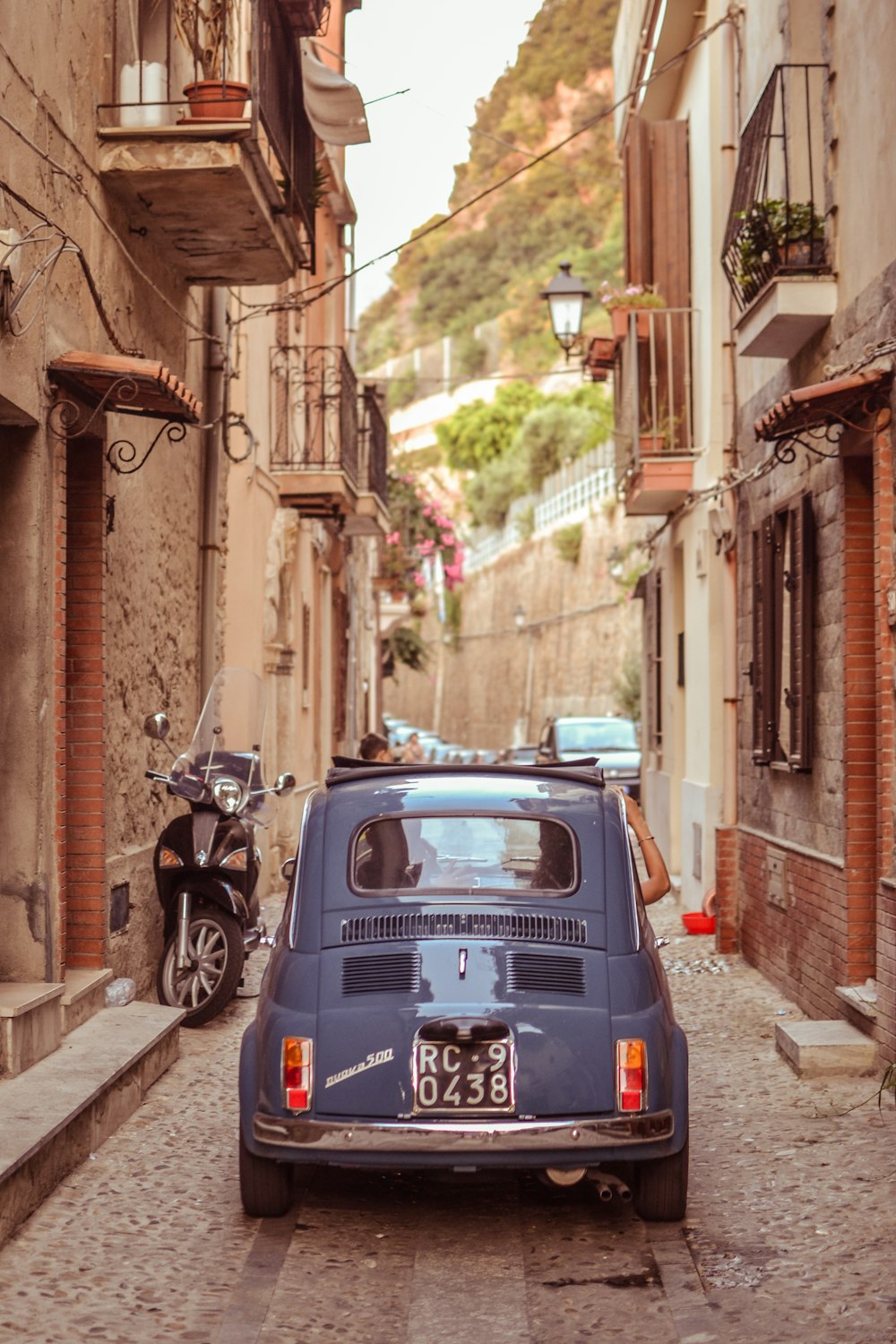 blue Volkswagen Beetle on narrow pathway between houses