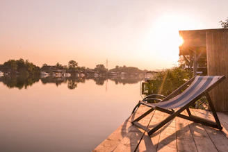 A serene lakeside patio with warm wood decking and matte black fixtures at sunset.