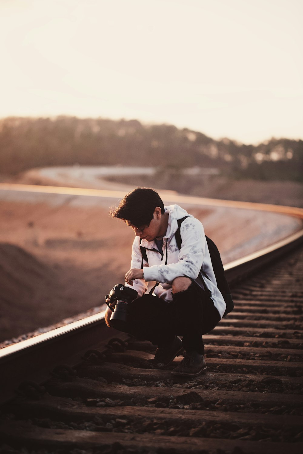 man sitting on train rail during daytime