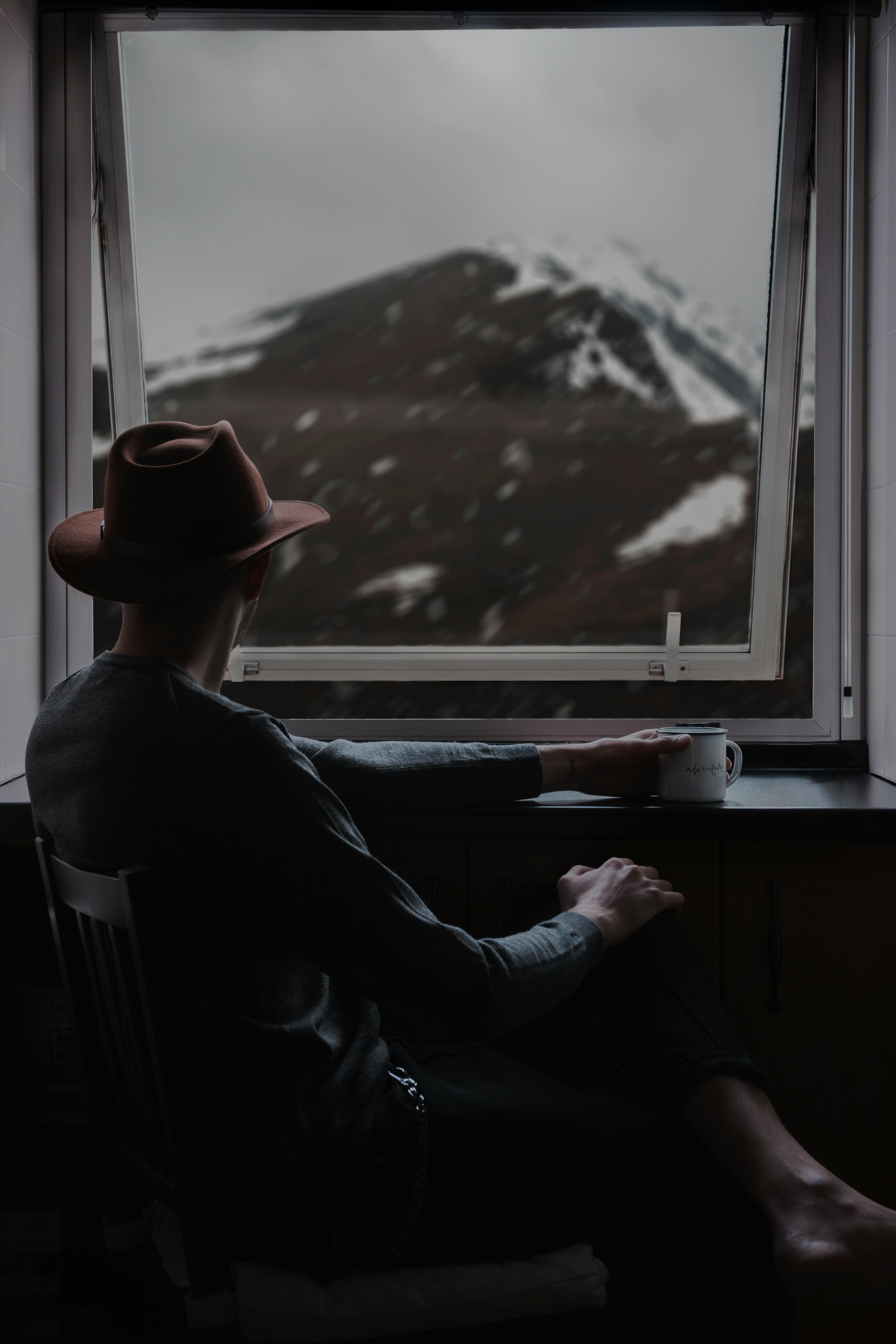 man sitting on chair while looing at window