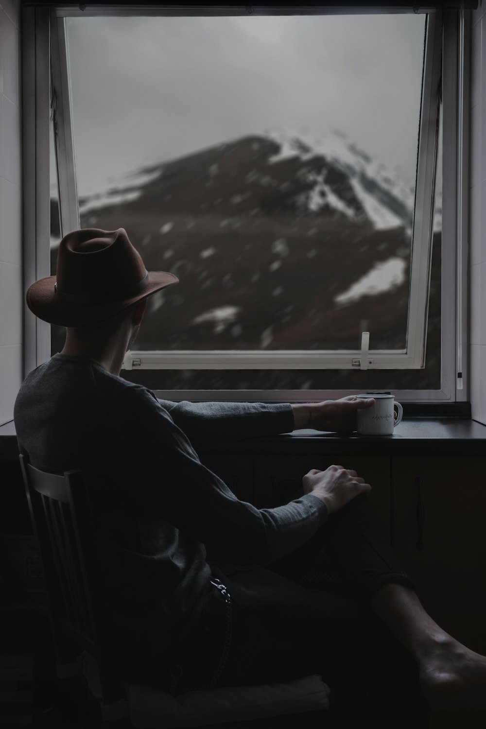 man sitting on chair while looing at window