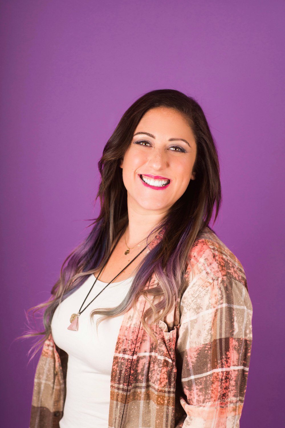 smiling woman in white t-shirt and brown and pink blazer