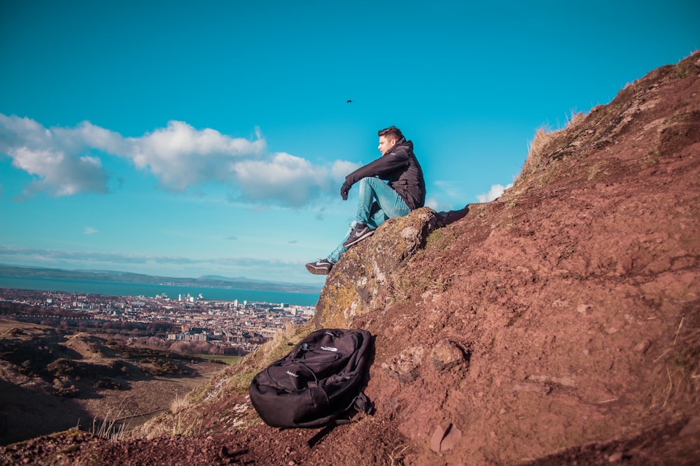 man sitting on mountain cliff