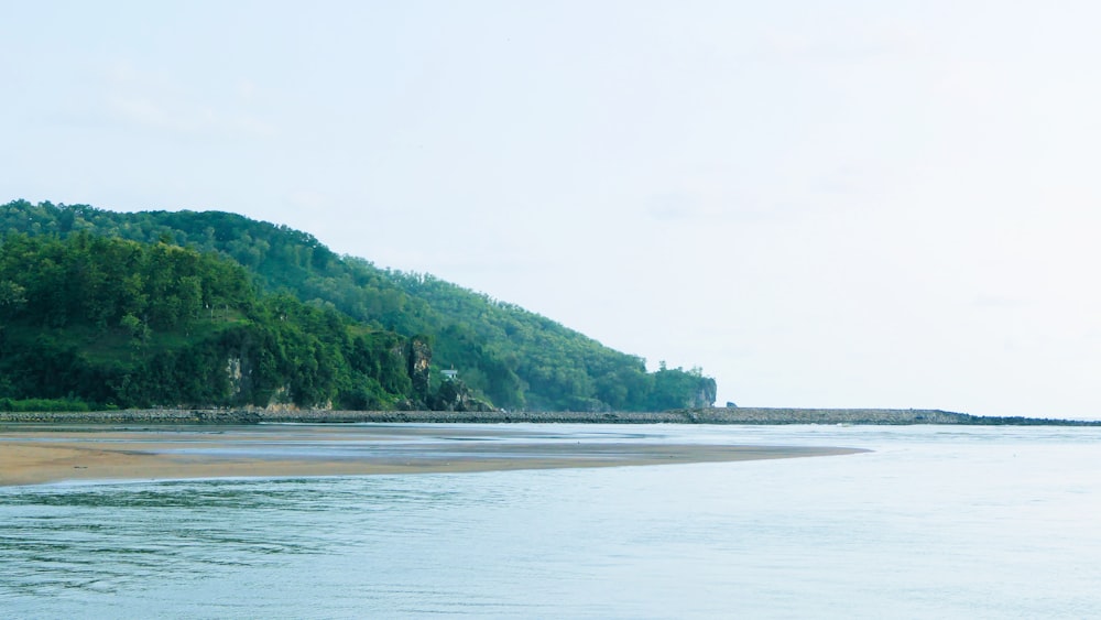 calm body of water near green mountain