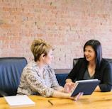 two women sitting on leather chairs in front of table