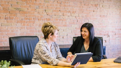 two women sitting on leather chairs in front of table