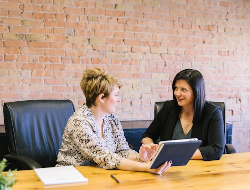 two women sitting on leather chairs in front of table