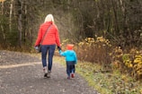 Siblings holding hands wearing matching colorful seasonal jackets in autumn leaves.