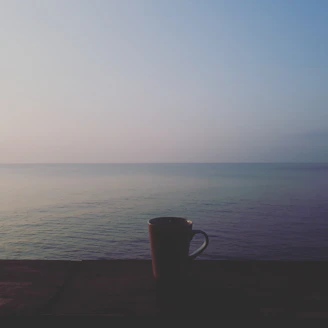 A serene morning scene with soft blue skies and a person enjoying a peaceful moment with a cup of tea.