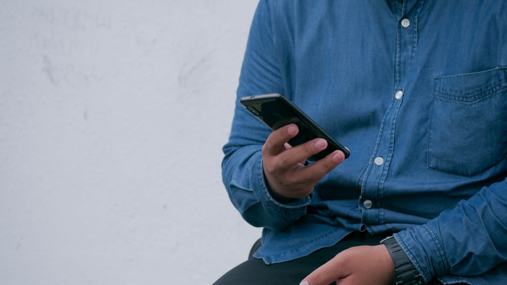 Person in blauer Jeansjacke mit Smarthone