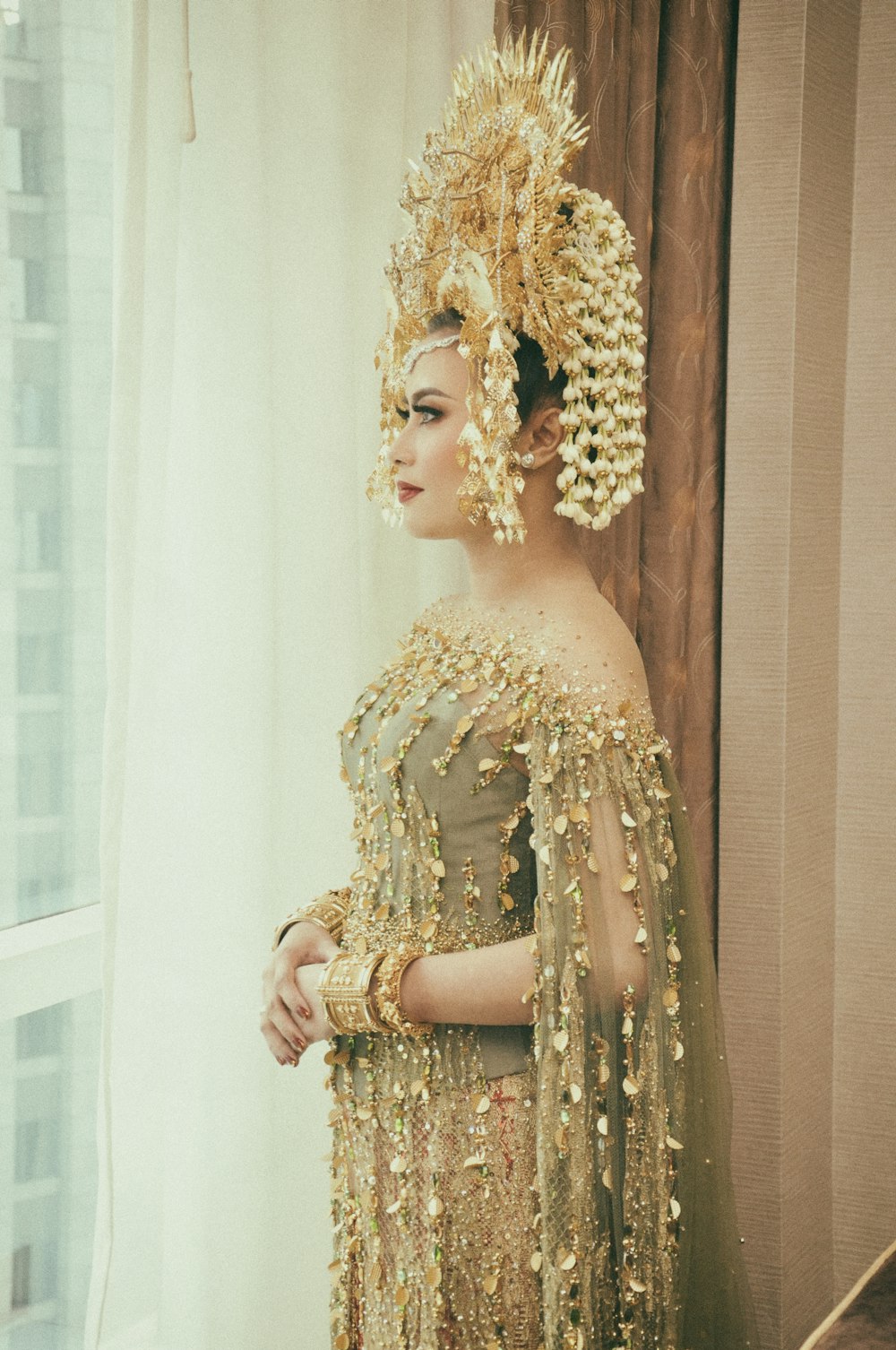 woman standing in front of window wearing brown off-shoulder dress