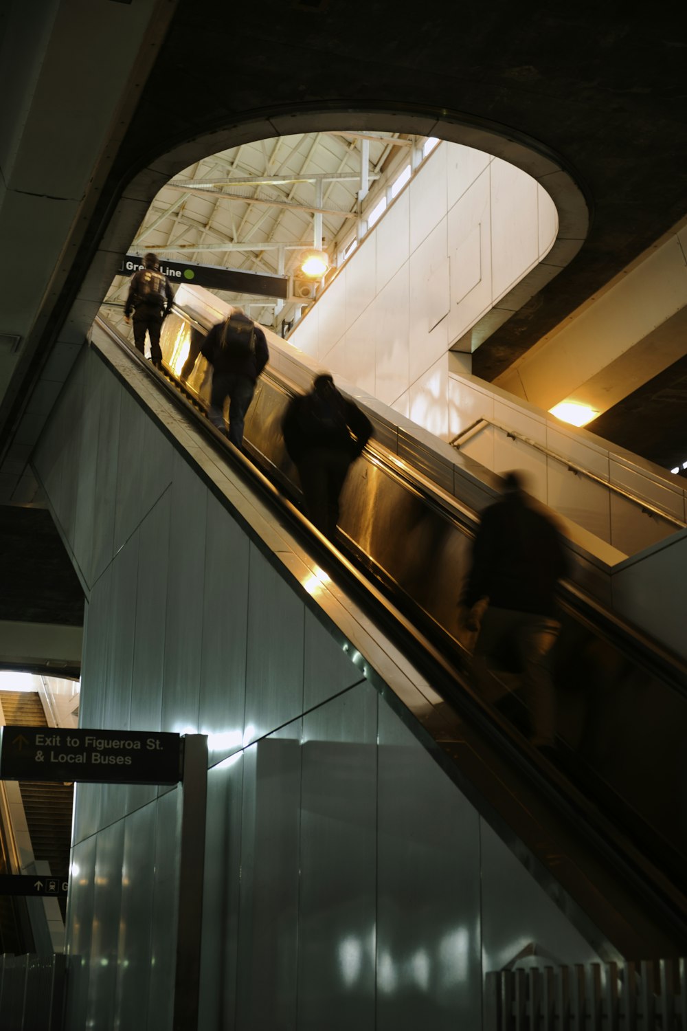 four people on escalator inside building