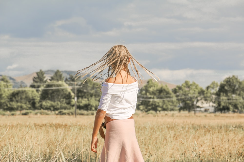 woman standing on brown grass field under blue sky