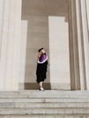 woman in academic regalia standing near concrete stairs