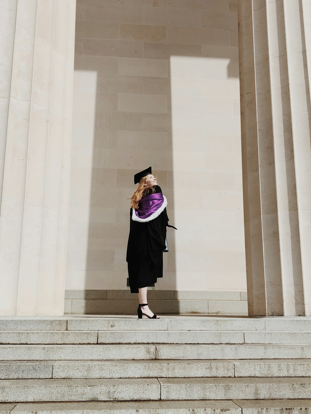 Mujer vestida de forma académica de pie cerca de las escaleras de hormigón