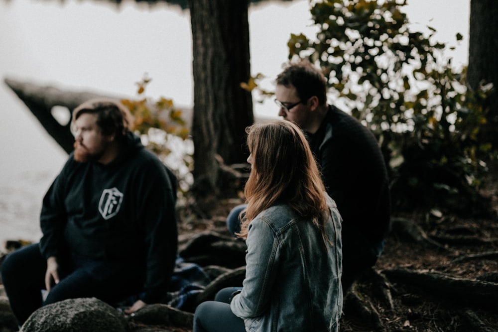 three men sitting near tree