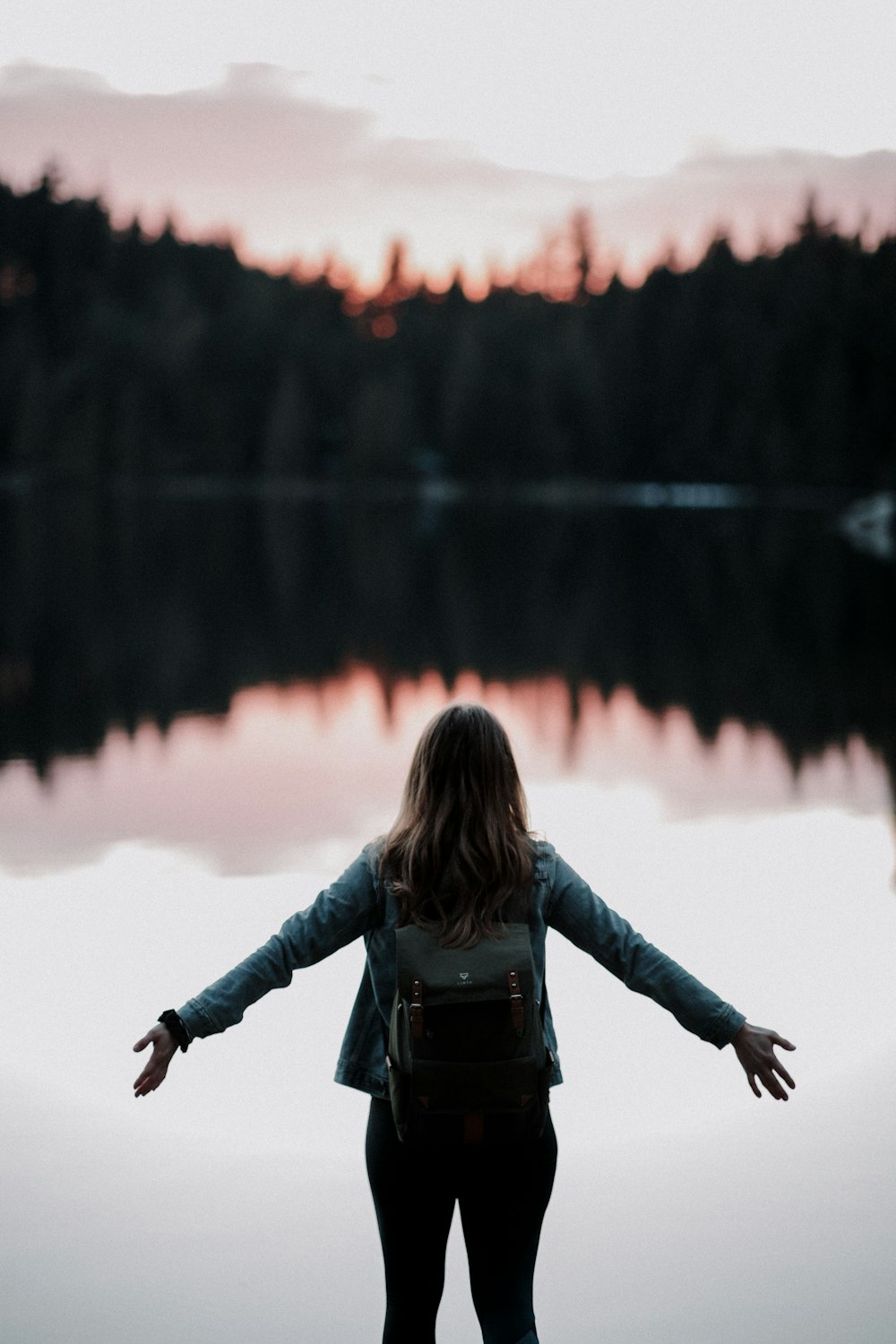 woman standing while facing on body of water