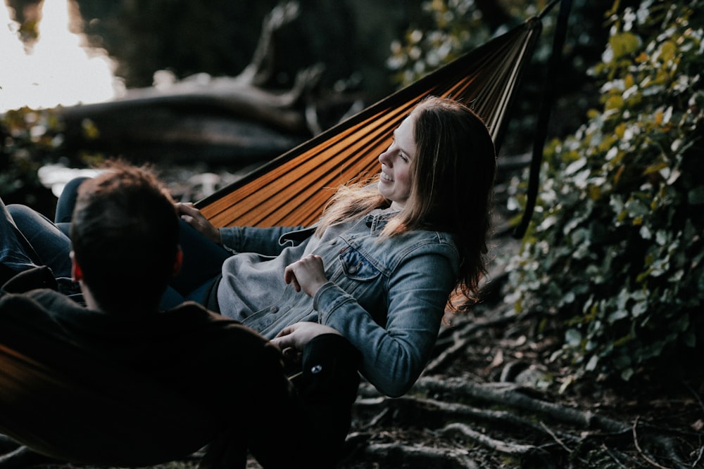 man and woman lying on hammock