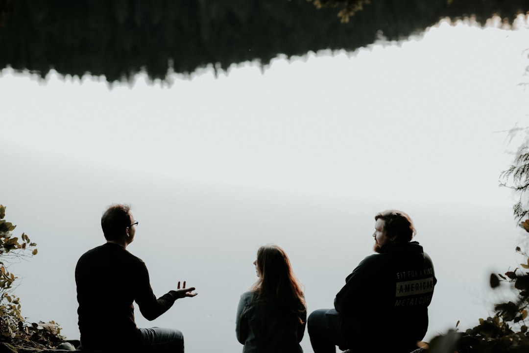 Two men and a woman sitting lakeside talking